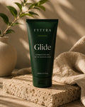 Fytyra Glide conductive gel, a 200ml deep green tube, standing on travertine beside linen