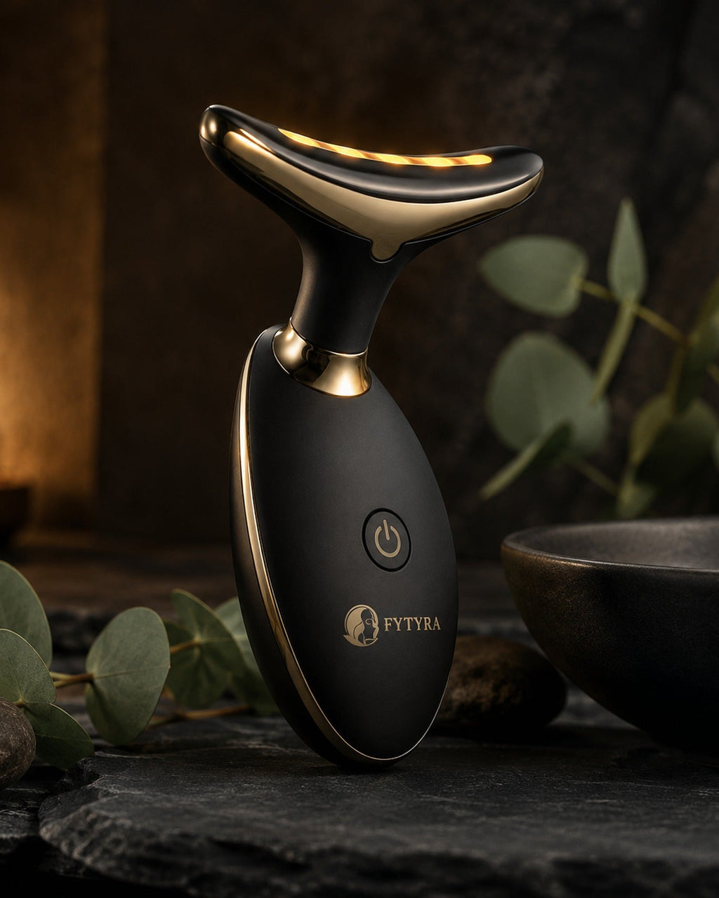 The Fytyra Sculpting Device in Midnight on dark slate beside candlelight and eucalyptus