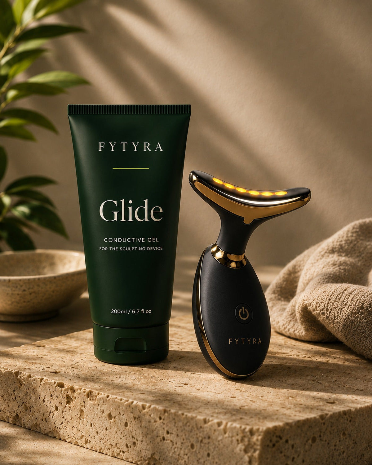 Fytyra Glide beside the Fytyra Sculpting Device in Midnight on a travertine ledge
